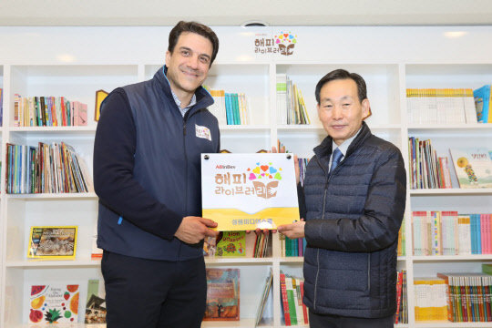 오비맥주는 서울 독산동에 지역아동들의 방과 후 학습공간인 '해피 라이브러리(행복도서관)'를 열었다. 지난달 30일 서울 독산동 성원미디어스쿨 지역아동센터에서 김도훈 오비맥주 대표(왼쪽)가 임동채 성원미디어스쿨 지역아동센터장에게 현판을 전달하고 있다. <오비맥주 제공>